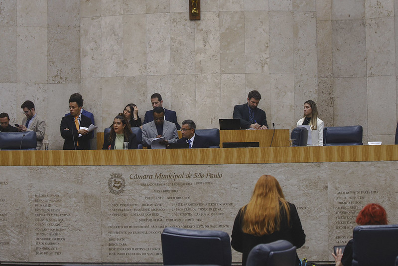 =Pessoas reunidas à mesa do Plenário da Câmara Municipal de São Paulo.